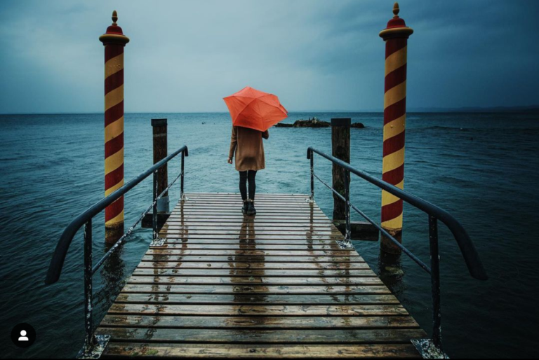 ragazza con ombrello arancione di fronte al lago